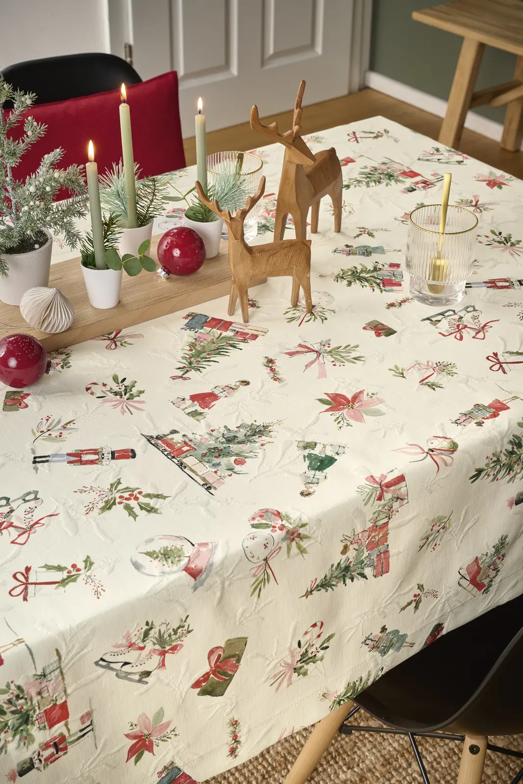 Festlich gedeckter Tisch mit weihnachtlicher Tischdecke, Kerzen und Holzhirschen